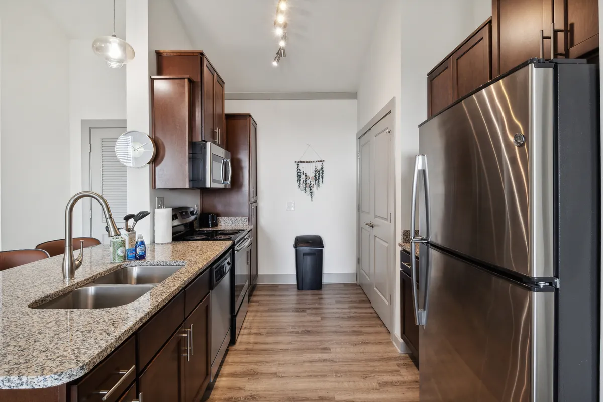A stylish kitchen featuring sleek granite countertops, stainless steel appliances, and warm wooden cabinetry. The space is arranged for functionality and entertaining, with ample prep areas and modern finishes that highlight a contemporary yet inviting atmosphere.