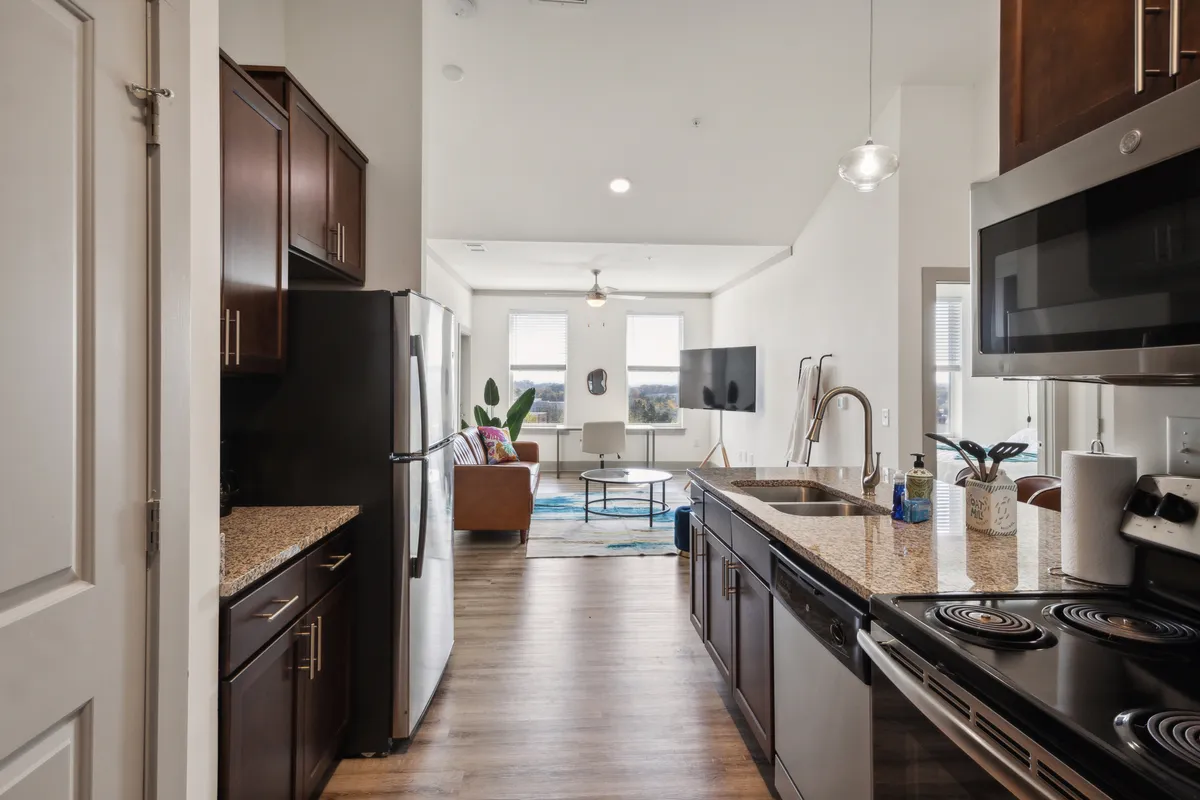 This interior photo showcases a contemporary kitchen and living area with granite countertops, modern appliances, comfortable seating, and large windows. The scene is lively yet cozy, ideal for both relaxing and staying connected—perfect for high-speed Wi-Fi and climate control benefits.